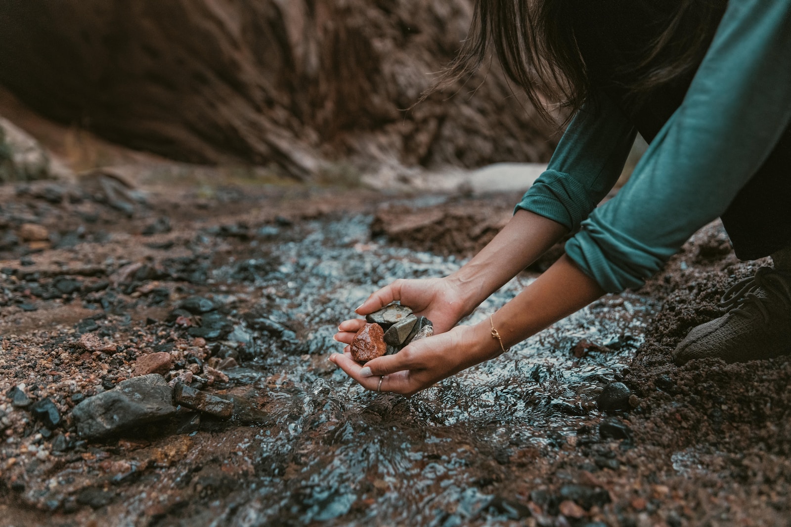 a person kneeling down and holding a rock in their hands