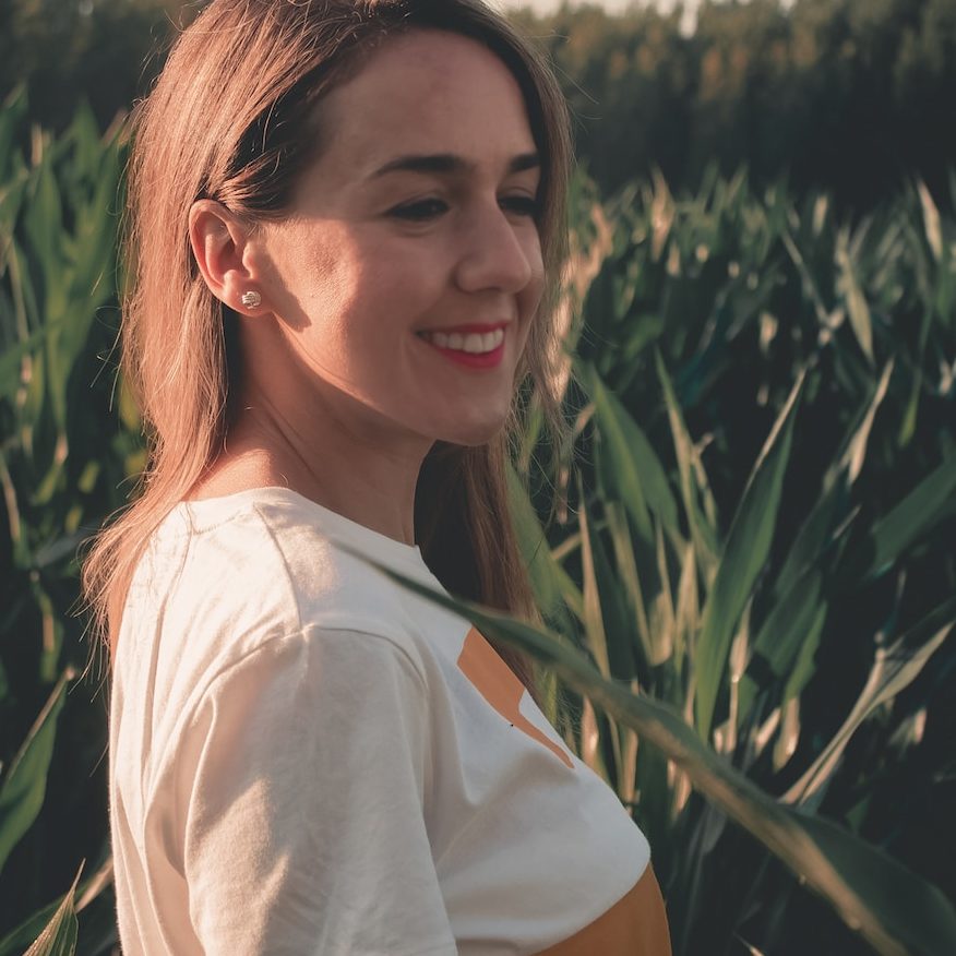 woman smiling beside green leaves during golden hour